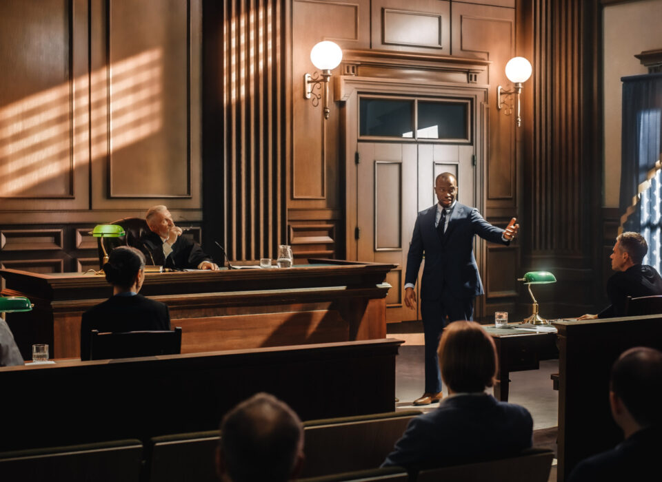 Court of Justice and Law Trial: Male Public Defender Presenting Court of Justice and Law Trial: Male Public Defender Presenting Case, Making Passionate Speech to Judge, Jury. African American Attorney Lawyer Protecting Client's Innocents with Supporting Argument.