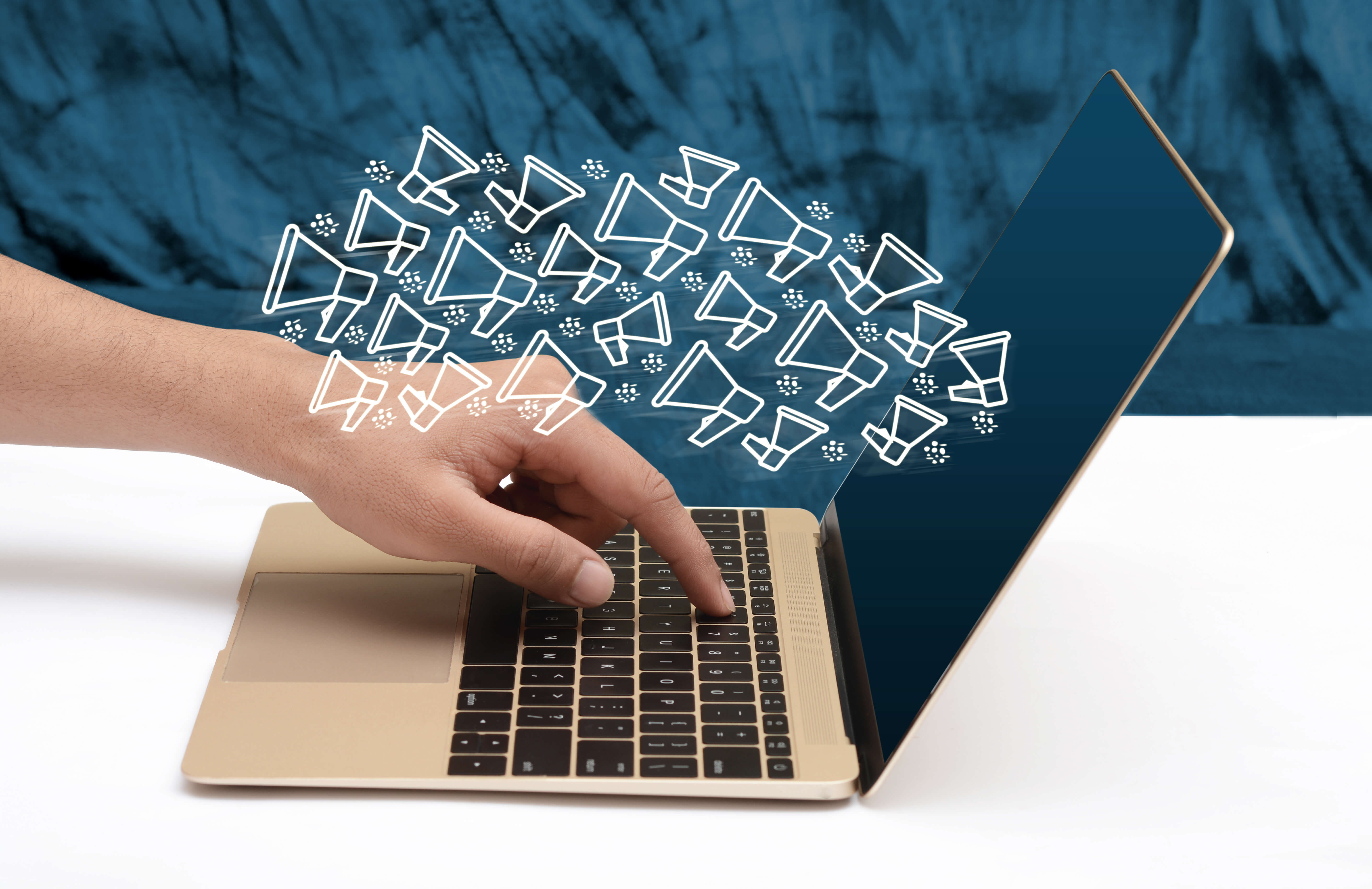 Hand typing on a laptop with email icons flying out, representing email marketing