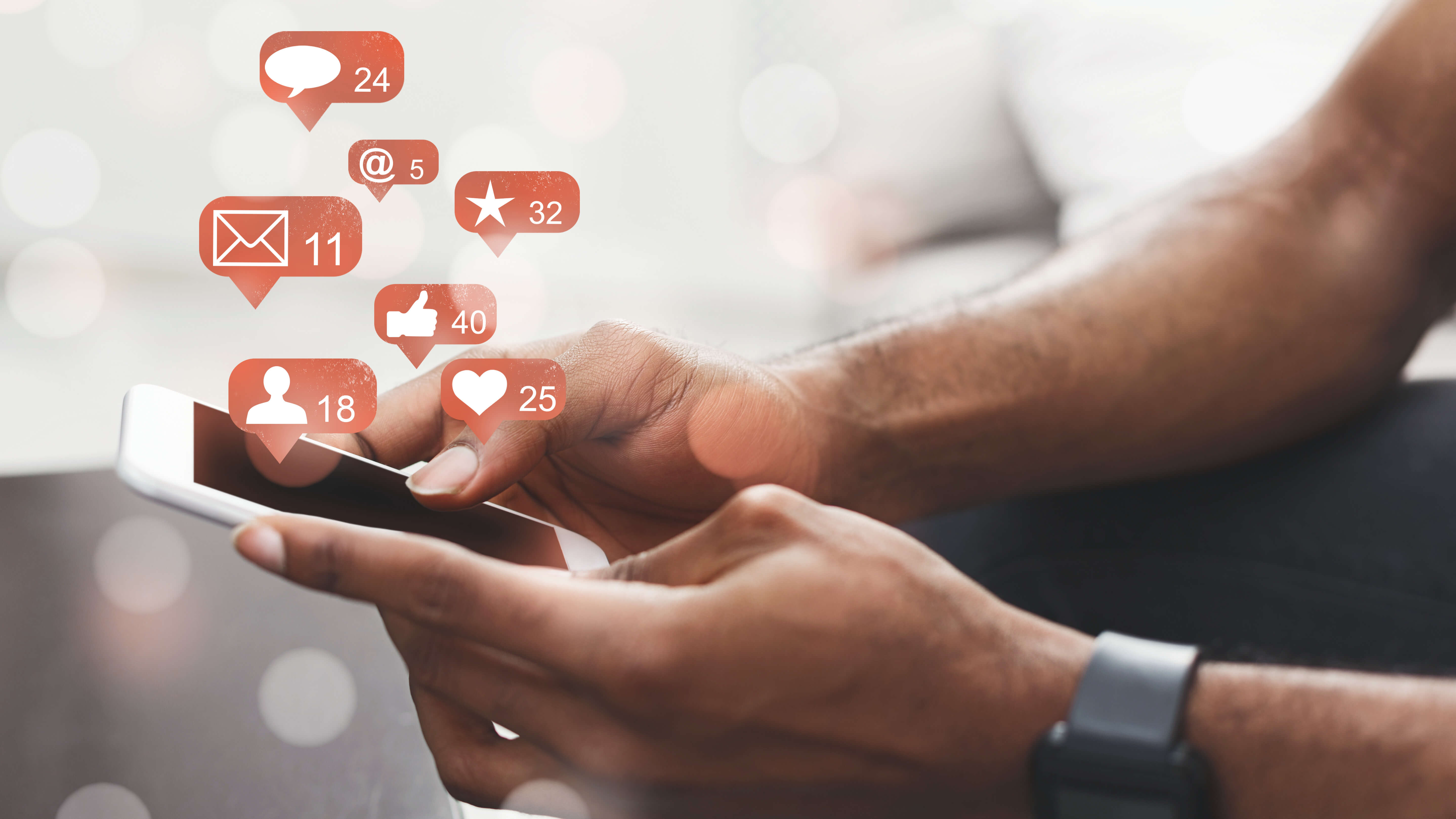 Person holding a smartphone with social media notification icons floating above it