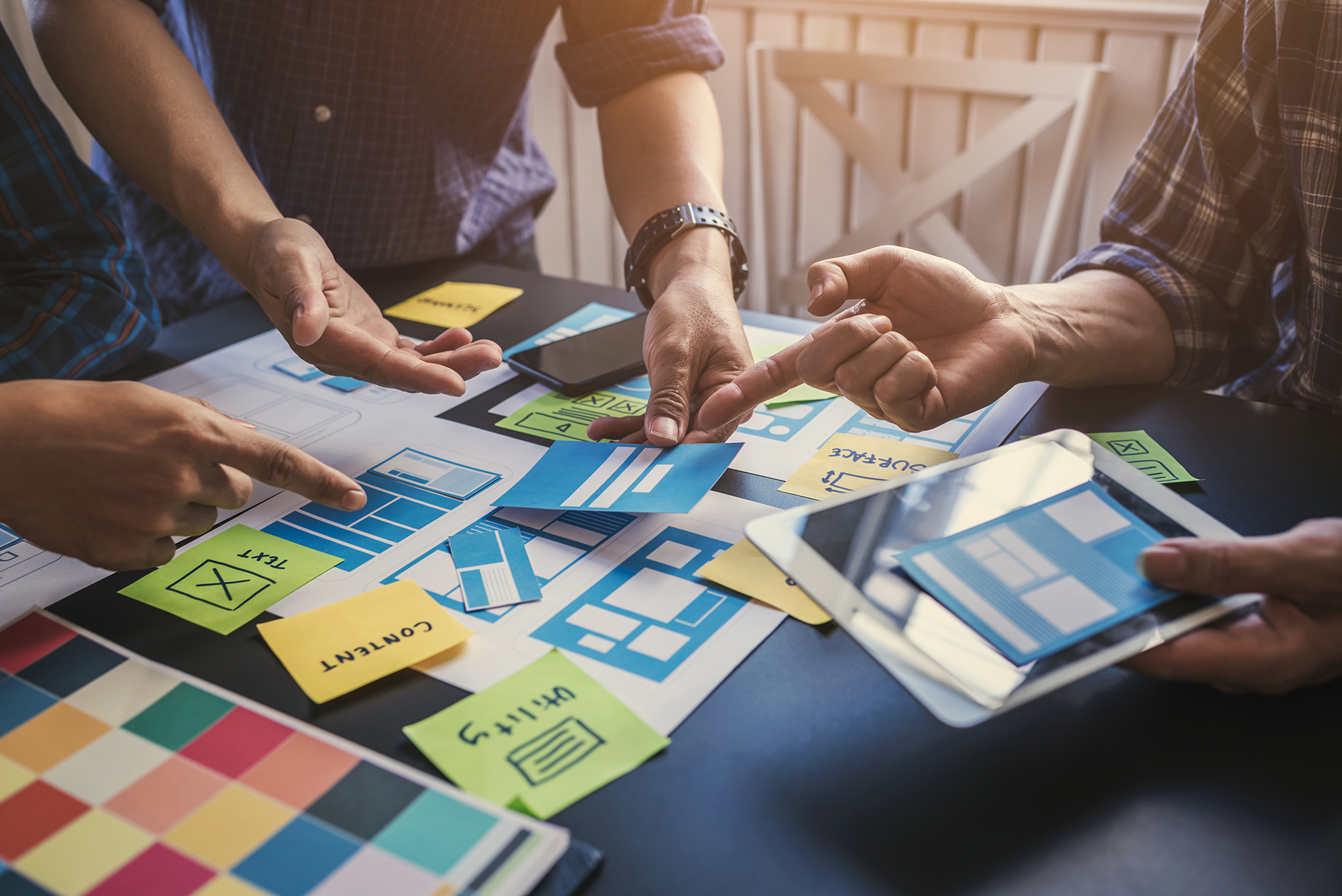 Team arranging content cards and color swatches on a table during a content strategy session