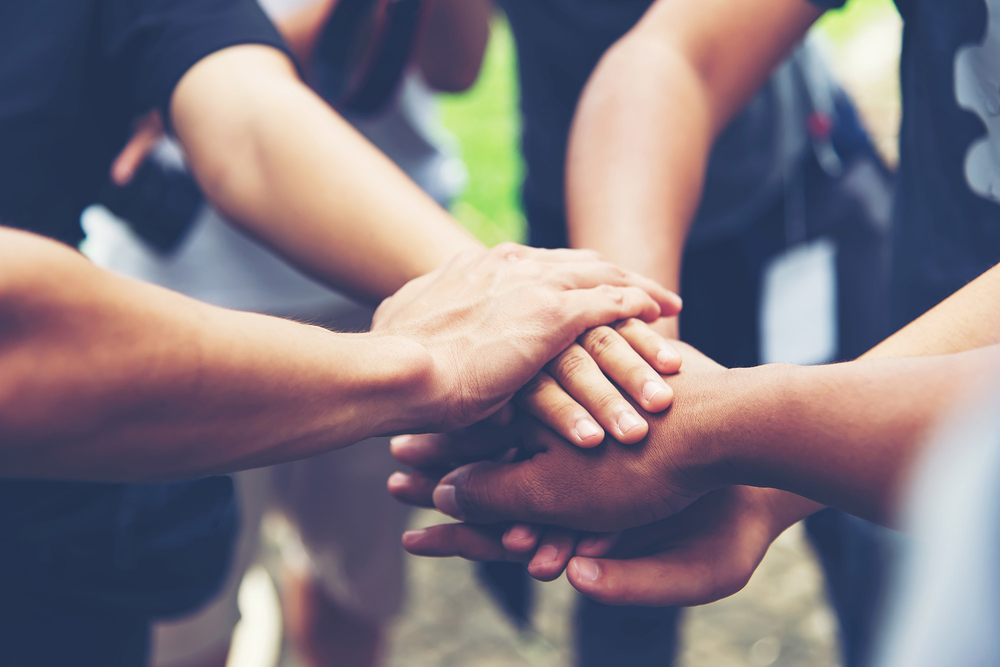 Group of people stacking their hands together in a show of teamwork - ironistic
