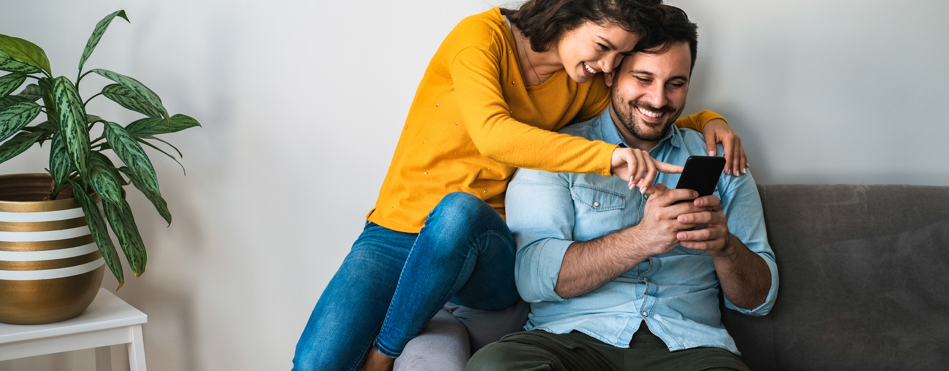Couple relaxing on a couch watching content on a smartphone