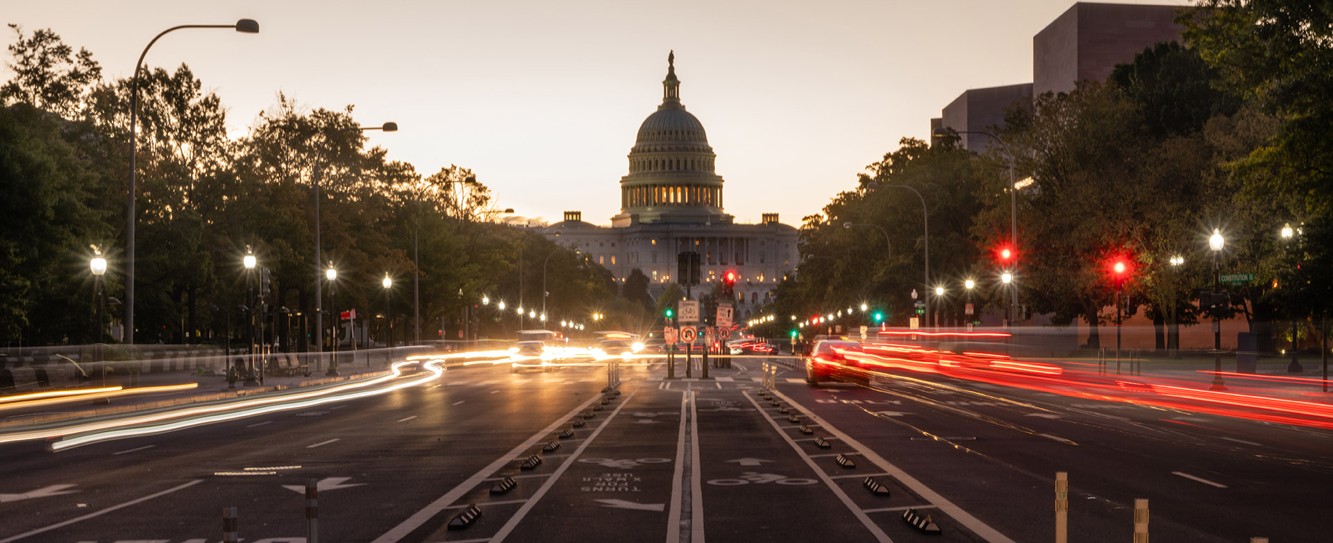 The U.S. Capitol at dusk with traffic light trails on the street
