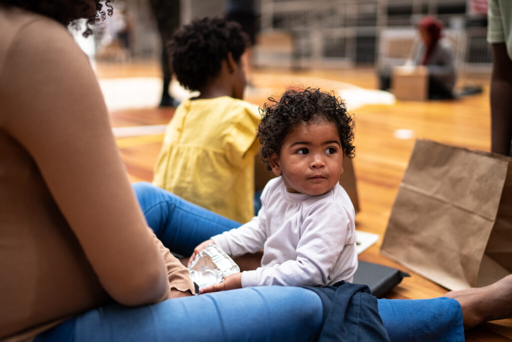 Young child sitting with a parent at a community charity event - ironistic
