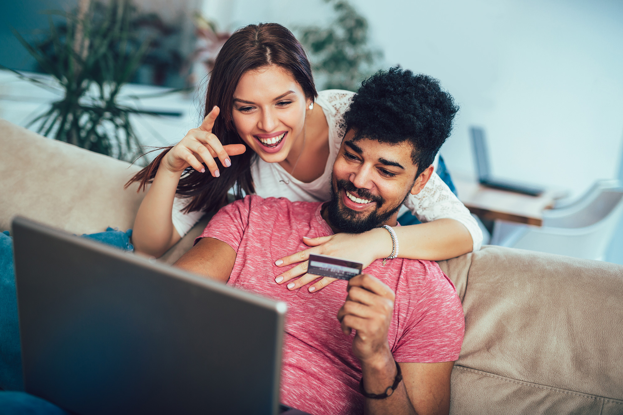 Smiling couple shopping online with a laptop and credit card at home - ironistic