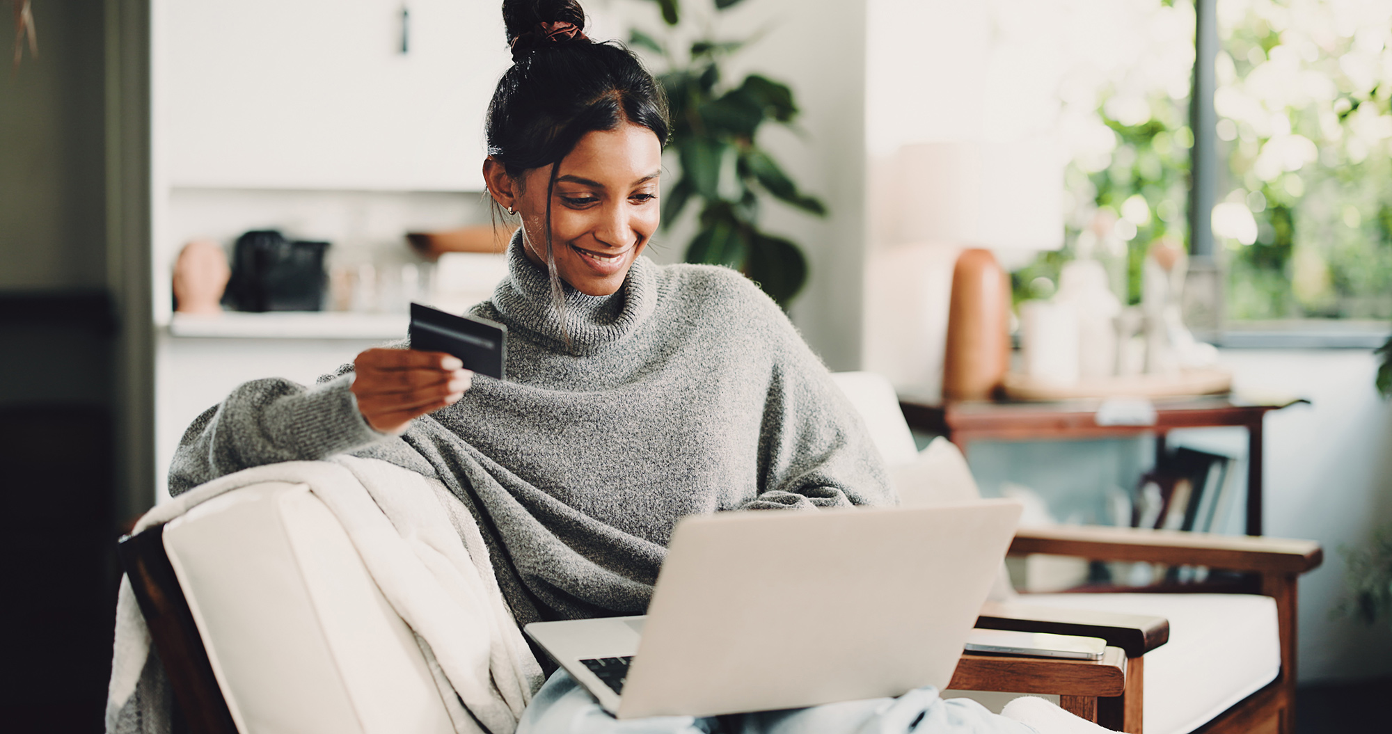 Woman using online banking on a laptop while holding a credit card