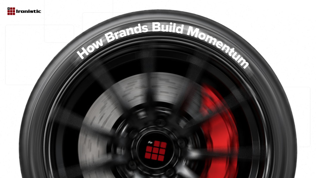 Spinning car wheel with red brake caliper and the Ironistic logo, text overlay reads 'How Brands Build Momentum
